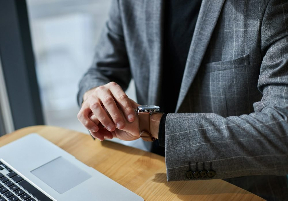 Close-up businessman in formal suit, checks the time on his wristwatch. Time management. Punctuality