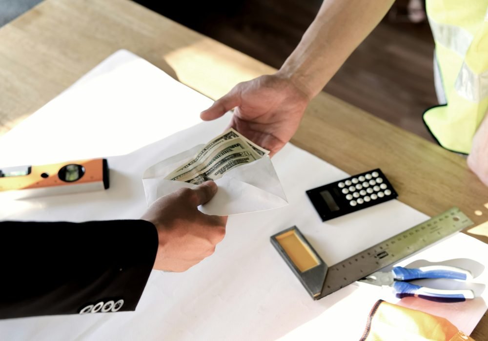 Top view of owner giving money to employee or hired person for his wage or salary over table.